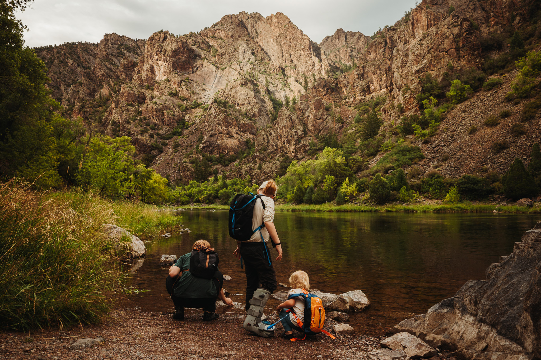 A family on a rocky overlook above a forested canyon at golden hour