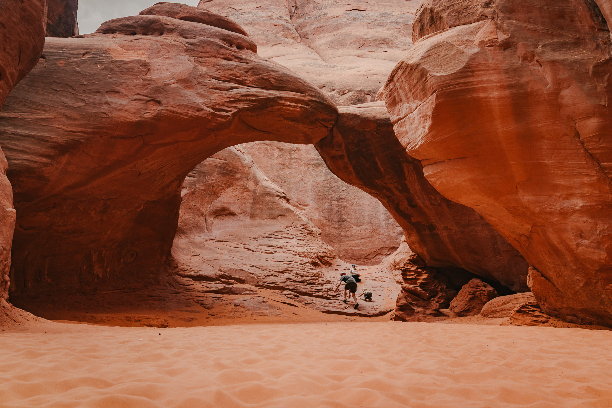 Small child in a red jacket walking through a red-rock slot canyon