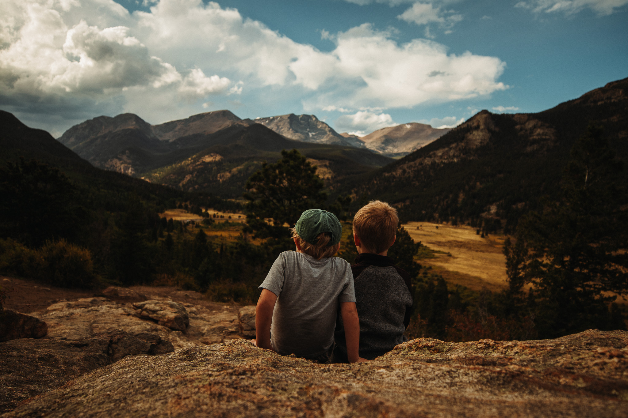 Parent and child wrapped in a blanket at sunrise on a mountain